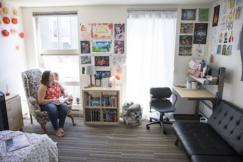 A student sits in a chair admiring her bedroom wall of posters.