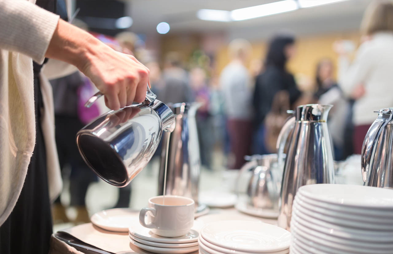 Conference attendee pouring coffee from a carafe.